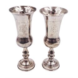 Pair of 1920s silver Kiddush cups, of typical form with engraved decoration, each upon knopped stem and stepped circular foot, hallmarked J Zeving (or Joseph Zweig), London 1920, H10cm