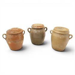 Three large 20th century Spanish stoneware confit pots and covers, each of ovoid form with twin loop handles to shoulders, and lift off covers, tallest example H43.5cm