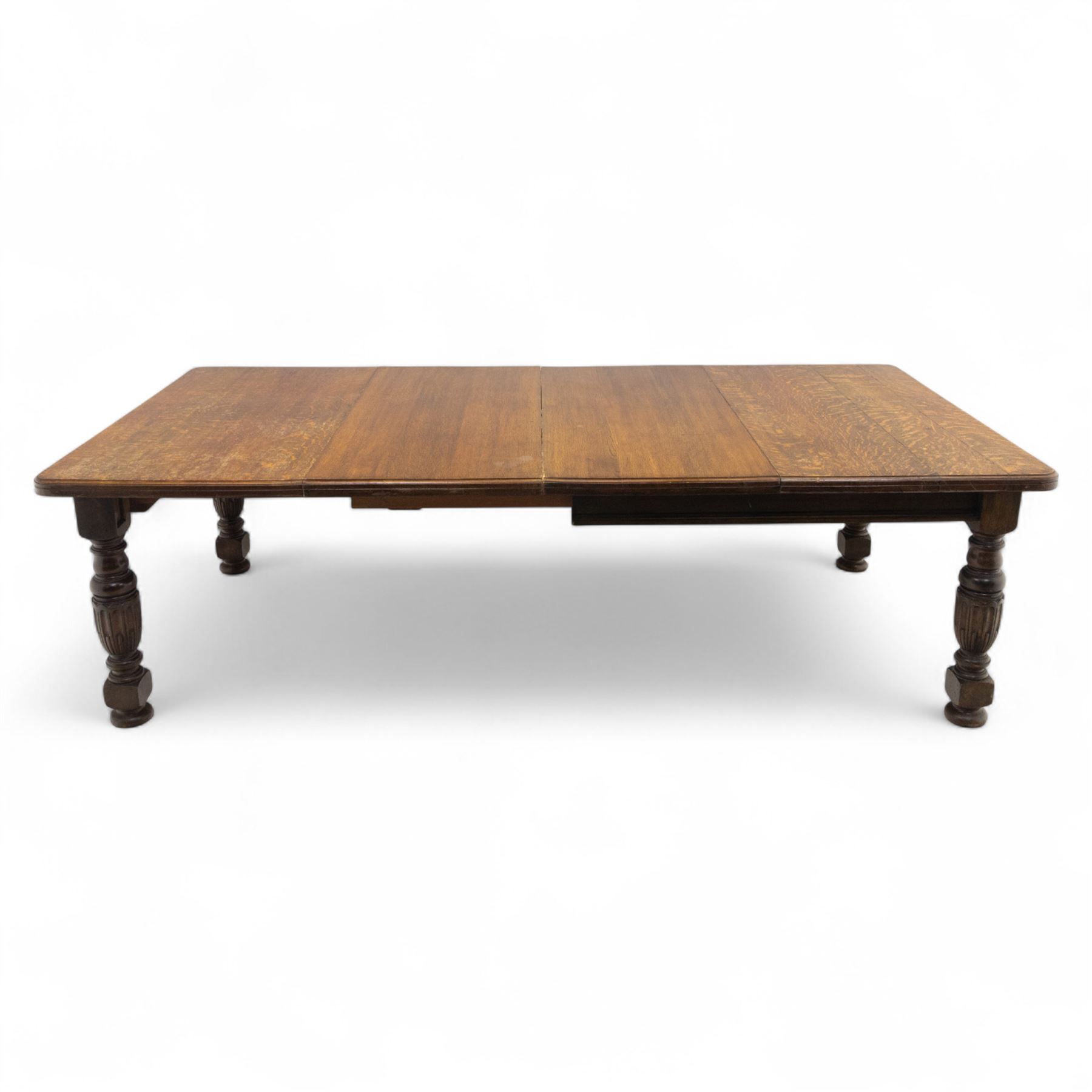 Victorian oak extending dining table, rectangular moulded top with figured grain pattern and wind-out action operated by removable crank handle, complete with additional leaves, raised on four boldly turned and reeded baluster supports terminating in squat bun feet (Extends to 238cm)