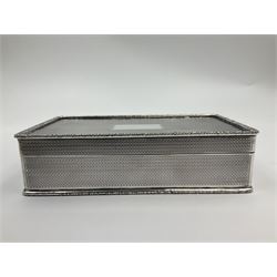 1920's silver table cigarette box, of rectangular form with engine turned decoration to the exterior, the hinged cover with central vacant rectangular panel and raised foliate rim, opening to reveal a gilt interior with later plush lining, hallmarked Charles Henry Dumenil, London 1923, H3.5cm L14.5cm D8.5cm