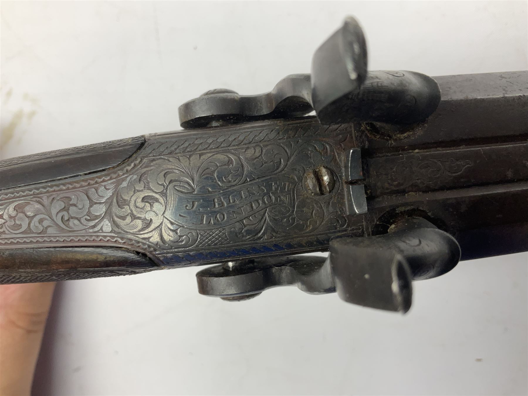 Early 19c percussion double barrel Howdah pistol by J. Blisset London, c1840s, approximately 50 calibre, 10.5cm octagonal monobloc barrels with captive swivel ramrod under, finely chequered walnut stock, engraved hammers, lock plates, tang and trigger guard, butt plate with hinged cap compartment, vacant white metal oval escutcheon L25.5cm overall