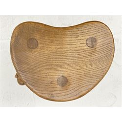 'Mouseman' oak three legged stool with dished kidney shaped seat, tapered octagonal supports, with carved mouse signature, by Robert Thompson of Kilburn 