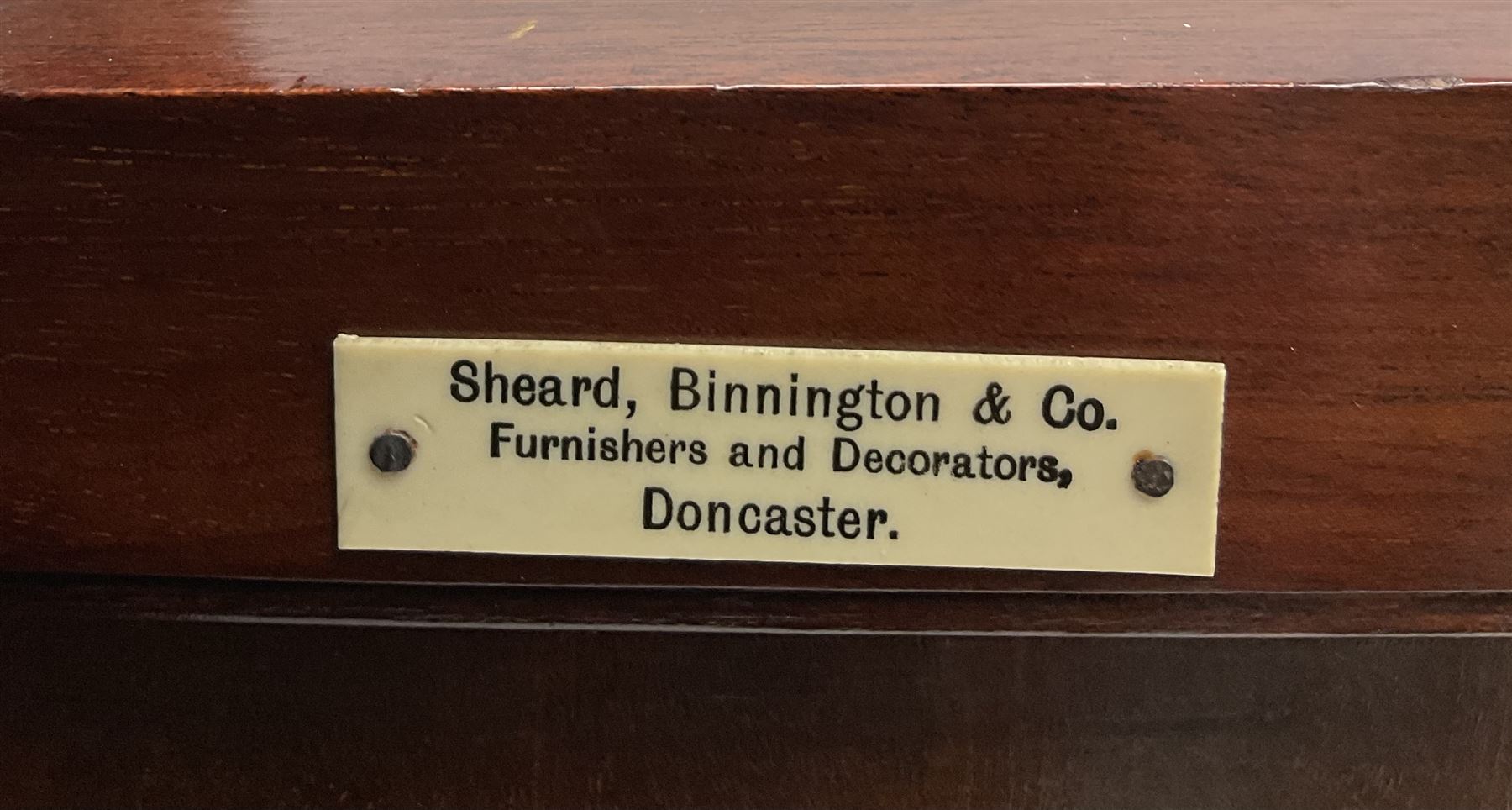 Edwardian inlaid mahogany display cabinet with ‘Shepard, Bennington & Co. Doncaster’ makers plaque, central bevel edge mirror flanked by two glazed doors enclosing two lined shelves, single drawer above cupboard on square tapering supports with spade feet