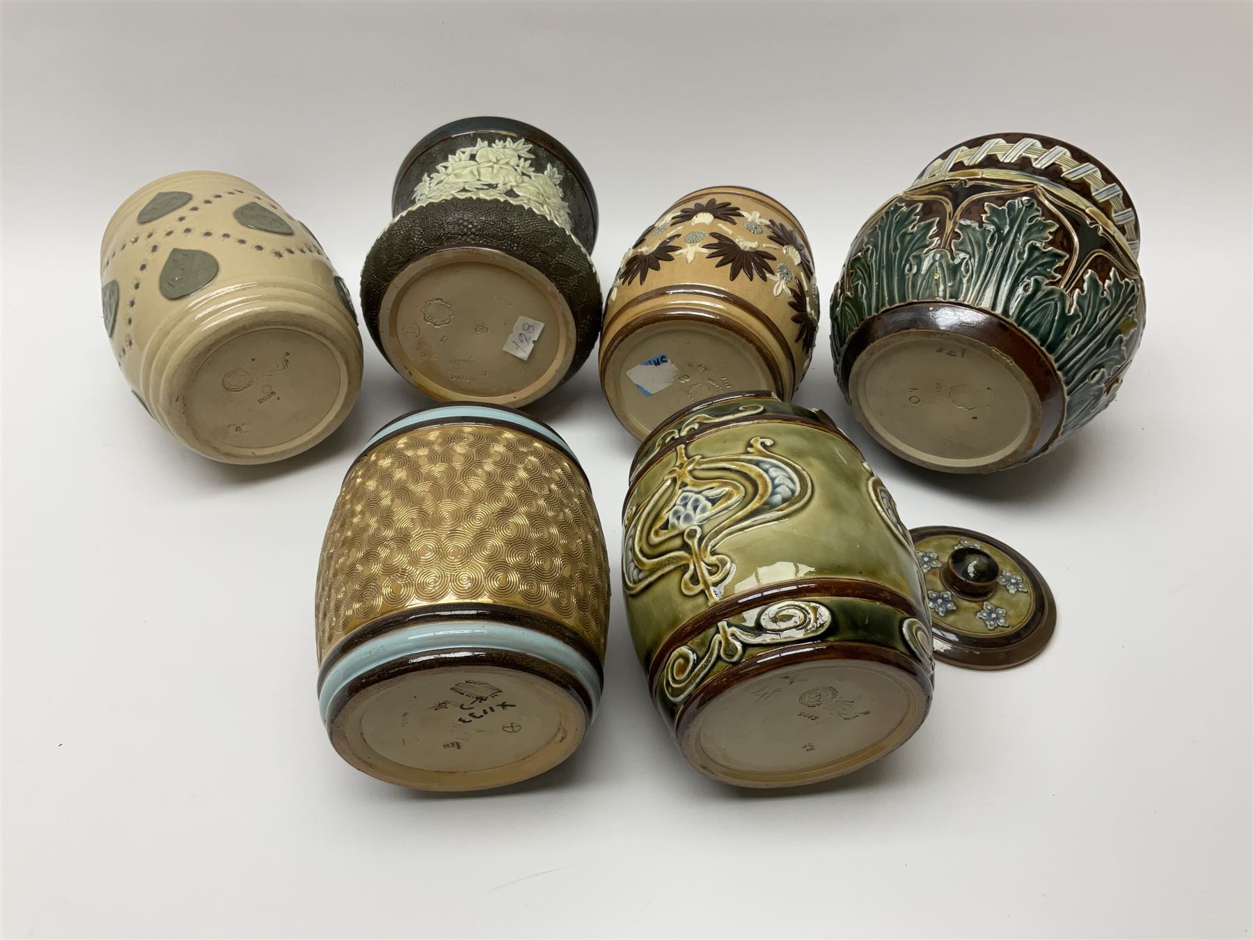 A group of Doulton Lambeth and Royal Doulton tobacco jars, to include examples with relief moulded foliate decoration, each with impressed marks and markers monograms beneath. 