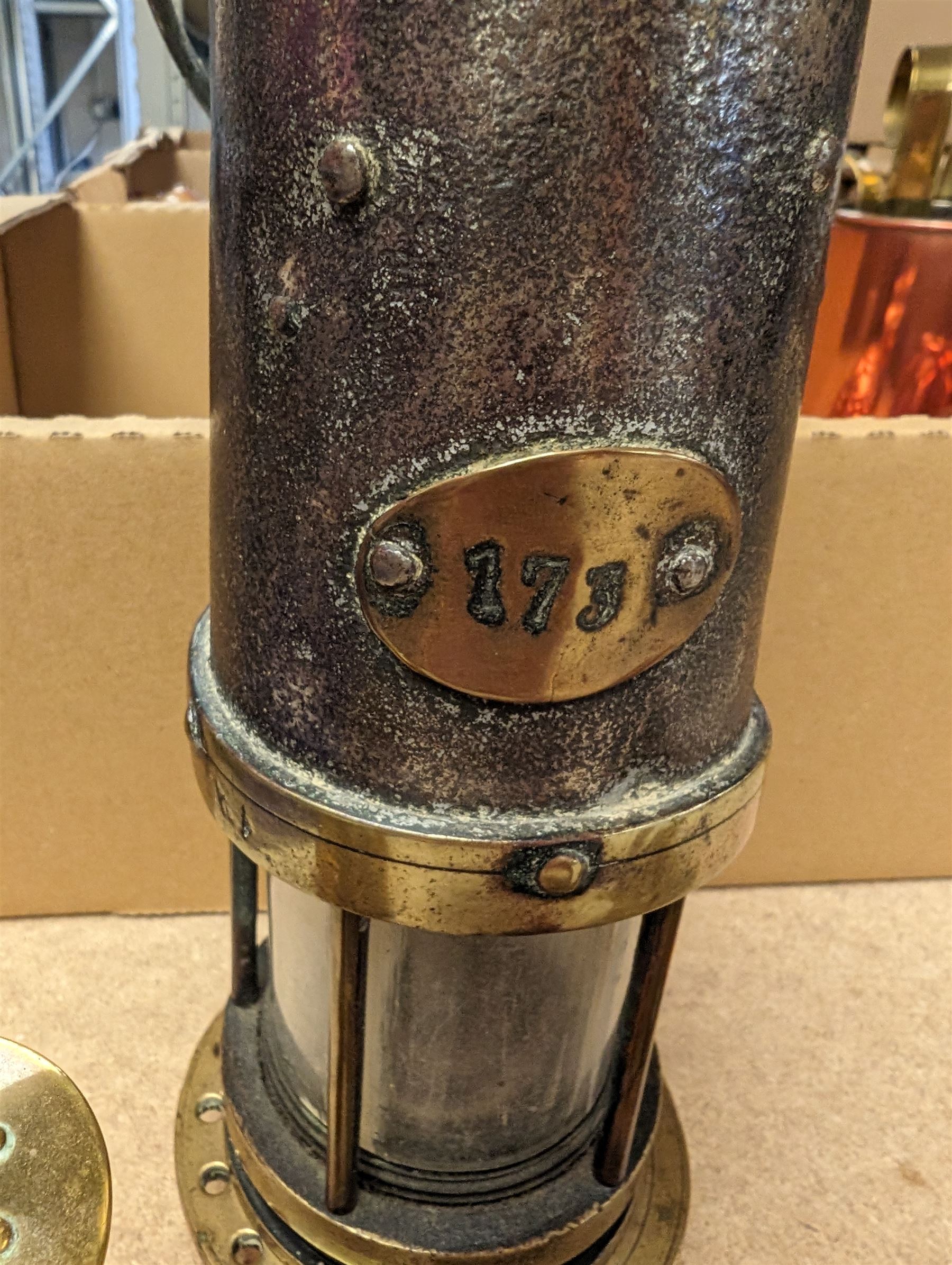 Miners lamp, with plaque numbered 173, together with a miniature brass miners lamp and a wooden paperweight with applied brass miners lamp, pick axe and shovel
