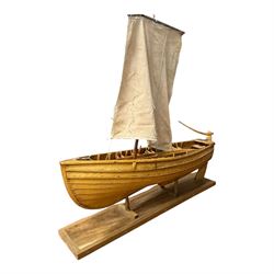 Wooden model of a fishing coble, with single canvas sail, upon a rectangular wooden plinth, total H74cm