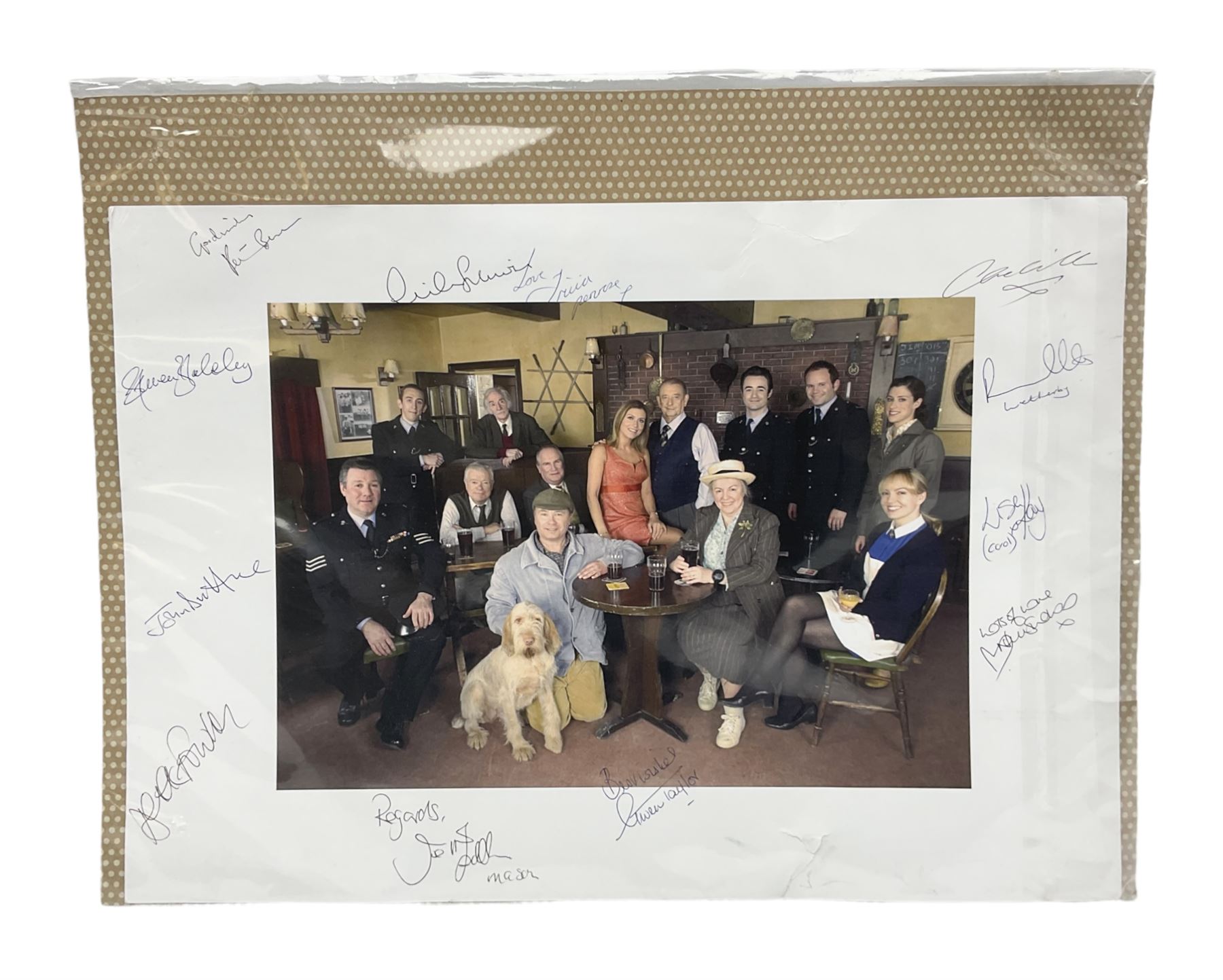 Photograph of the cast of Heartbeat posing in costume in the Aidensfield Arms and signed by twelve cast members including John Duttine, Tricia Penrose, Clare Wille, Derek Fowlds, Gwen Taylor, Lisa Kay, Peter Benson etc; unframed