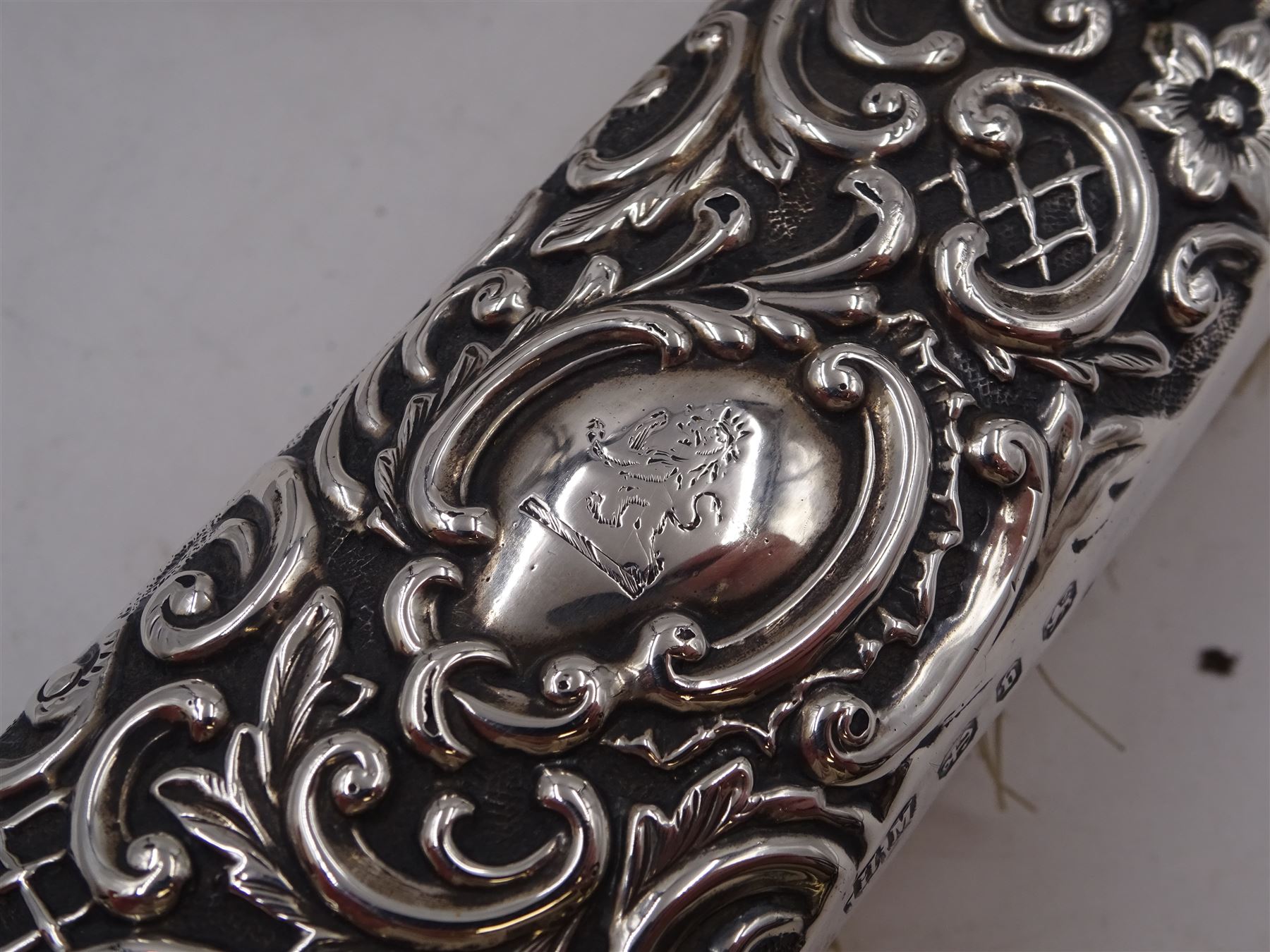 Group of silver, comprising Victorian silver hair brush and matching clothes brush, with repousse floral and scroll decoration, and each engraved with lion rampant to central cartouche, hallmarked Henry Matthews, Birmingham 1895, together with a 1920s miniature silver mounted photograph frame, hallmarked Charles Edwin Turner, Birmingham 1925 H7cm, and a Georgian silver Hanoverian pattern teaspoon, with scroll decoration to underside of bowl and engraved initials verso, hallmarks worn and indistinct