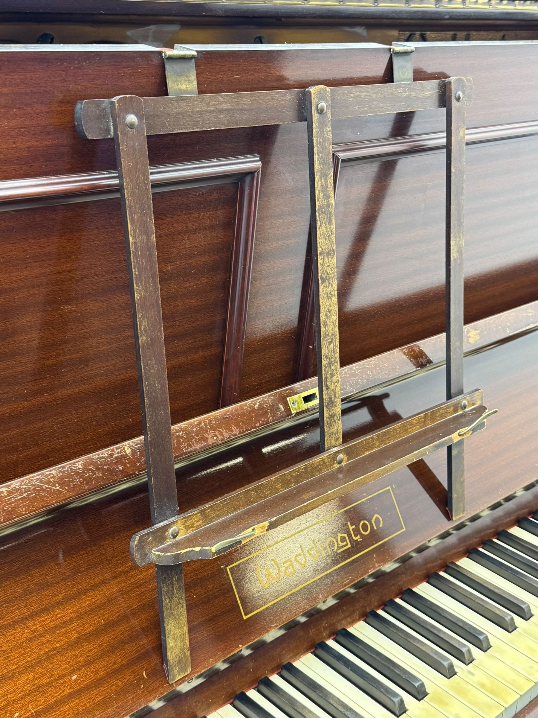 Waddington - Edwardian mahogany upright piano, rectangular top with panelled front, rounded key cover, makers name on fallboard, raised on bracket supports with castors