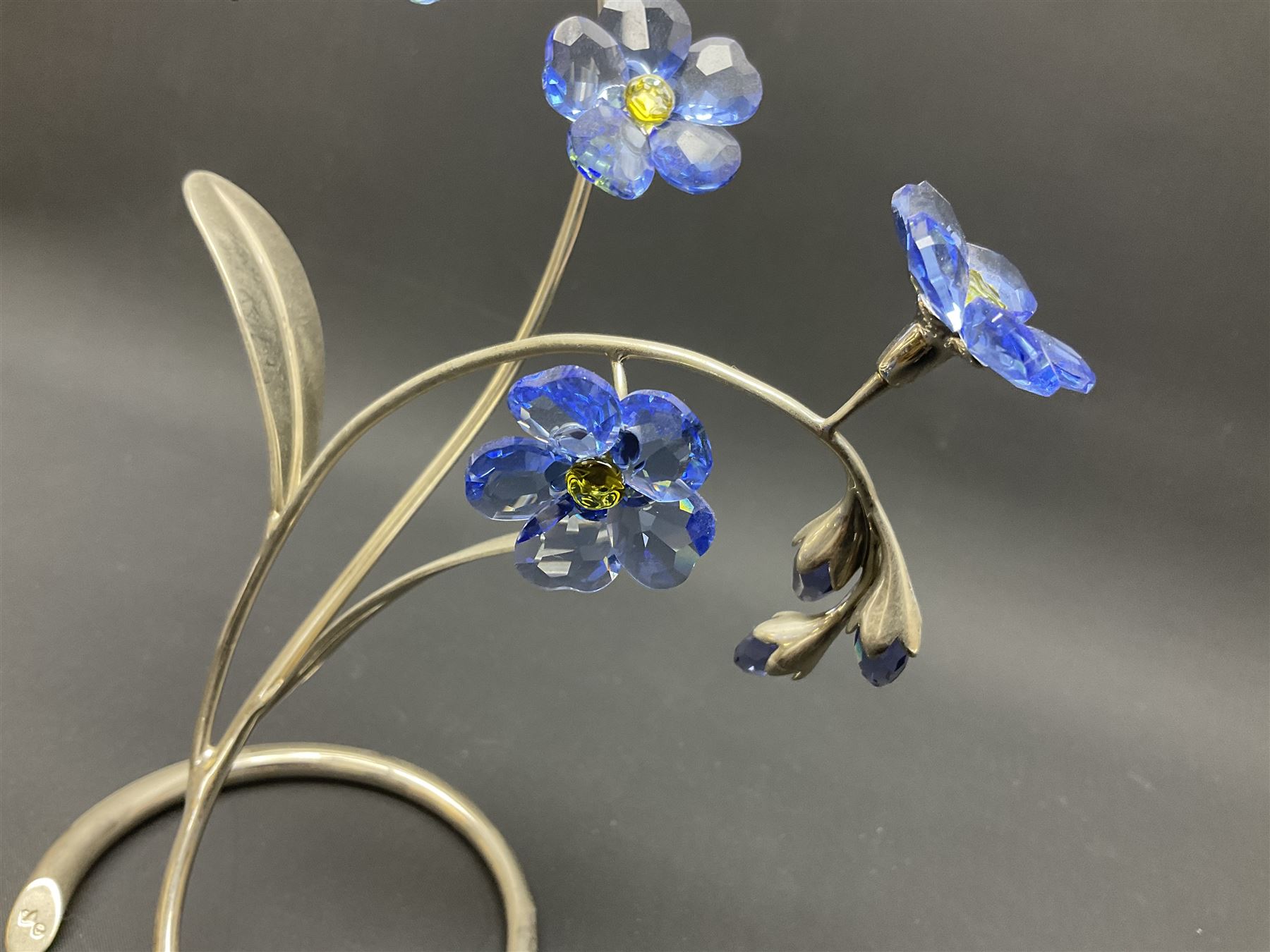 Eleven Swarovski Crystal flowers, to include violet, sunflower, delphinium, forget-me-not and lily-of-the-valley, each on stylised metal stems, tallest H23cm