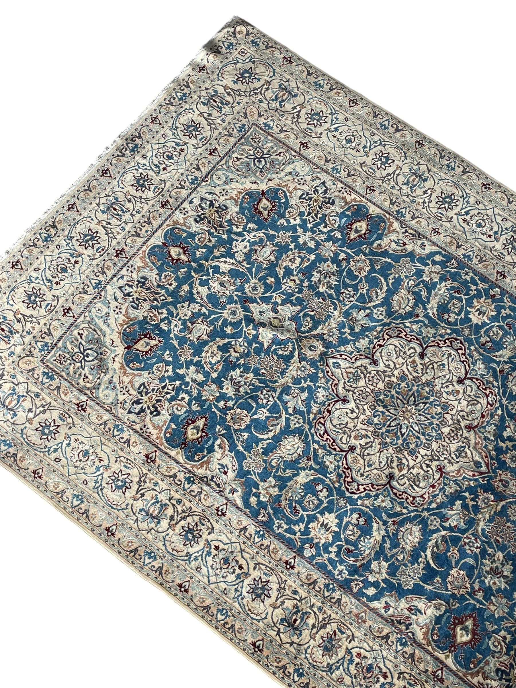 Persian Nain blue and ivory ground rug, wool with silk inlay, overall arabesque design, central medallion surrounded by interlacing and scrolled leafy branches and palmettes, the scrolling border decorated with stylised plant motifs, within guard stripes
