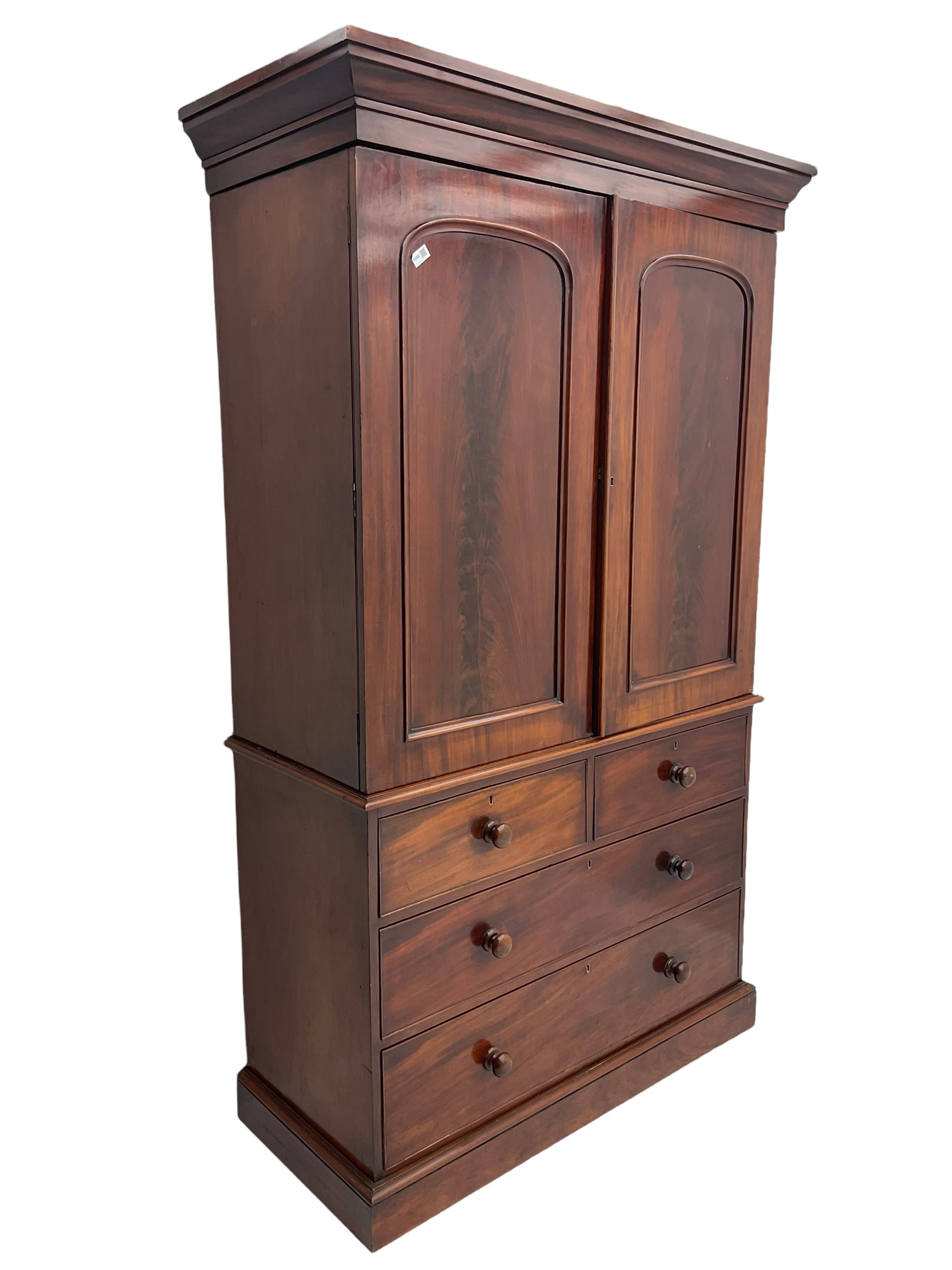 Victorian mahogany linen press, projecting moulded cornice, two doors with arched panels enclosed four linen slides, the lower section fitted with two short and two long drawers, on plinth base