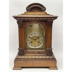 Late 19th/early 20th century walnut bracket clock, the architectural case with arched pediment over projecting egg and dart cornice, arched bevelled glazed door with fluted upright pilasters, engraved brass dial with silvered Roman chapter ring, 'Junghans' triple train quarter chiming movement, stepped egg and dart base