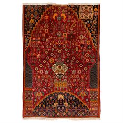 North Persian crimson ground rug, the field densely decorated with stylised flowering plan...