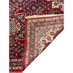 Persian design crimson ground rug, the field decorated with central floral pole medallion and surrounded by foliate patterns with matching spandrels, guarded border with repeating palmette motifs