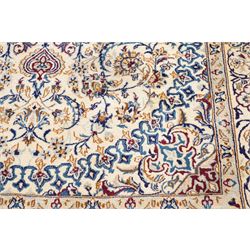 Persian Nain ivory ground rug, the busy oval field profusely decorated with scrolling foliate decoration and palmettes in citrine and indigo tones, the central medallion with matching spandrels, the multiple guard bands with repeating stylised quatrefoil motifs and trailing scrolling foliage and flowerheads