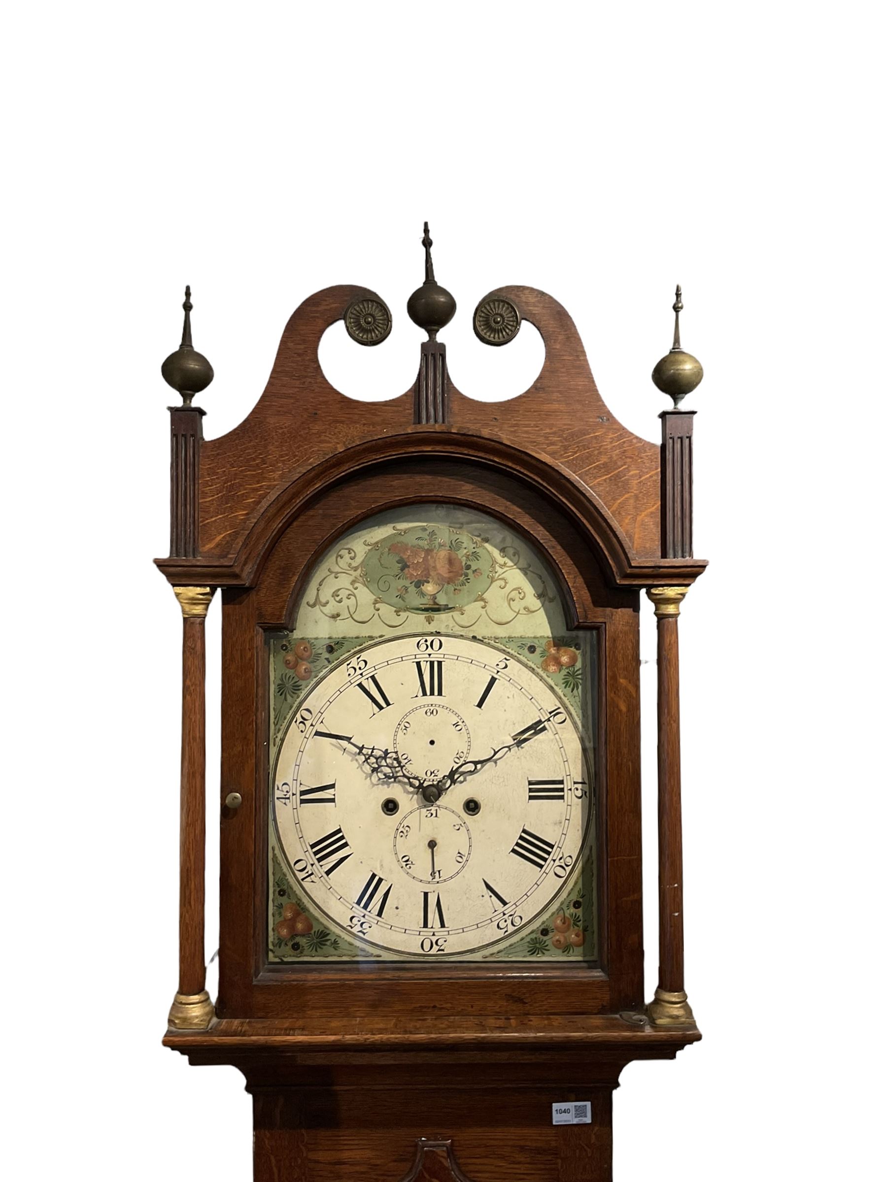 English oak cased longcase clock c1830, tall swan neck pediment with three ball and spire finals and brass paterae, break arch hood door flanked by two tapered columns with gesso capitals, with a slim trunk and full length door with a decorative ogee spire, on a square plinth with applied skirting, painted break-arch dial with depictions of flowers to the spandrels and break arch, spandrels and arch with raised gesso detailing on a green background, dial with Roman numerals and five-minute Arabic's, minute track, subsidiary date and seconds dial, with steel hands and calendar pointer (no second's hand), dial pinned via a cast falseplate to an eight-day rack striking movement, striking the hours on a bell. With weights,  pendulum and key.

