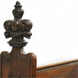 Late 19th century Gothic revival oak church pew, with high backrest framed by carved stylised cross panels and crown-topped finials, shaped end panels with scroll detailing, on block end supports and central stretcher, with later padded seat cushion