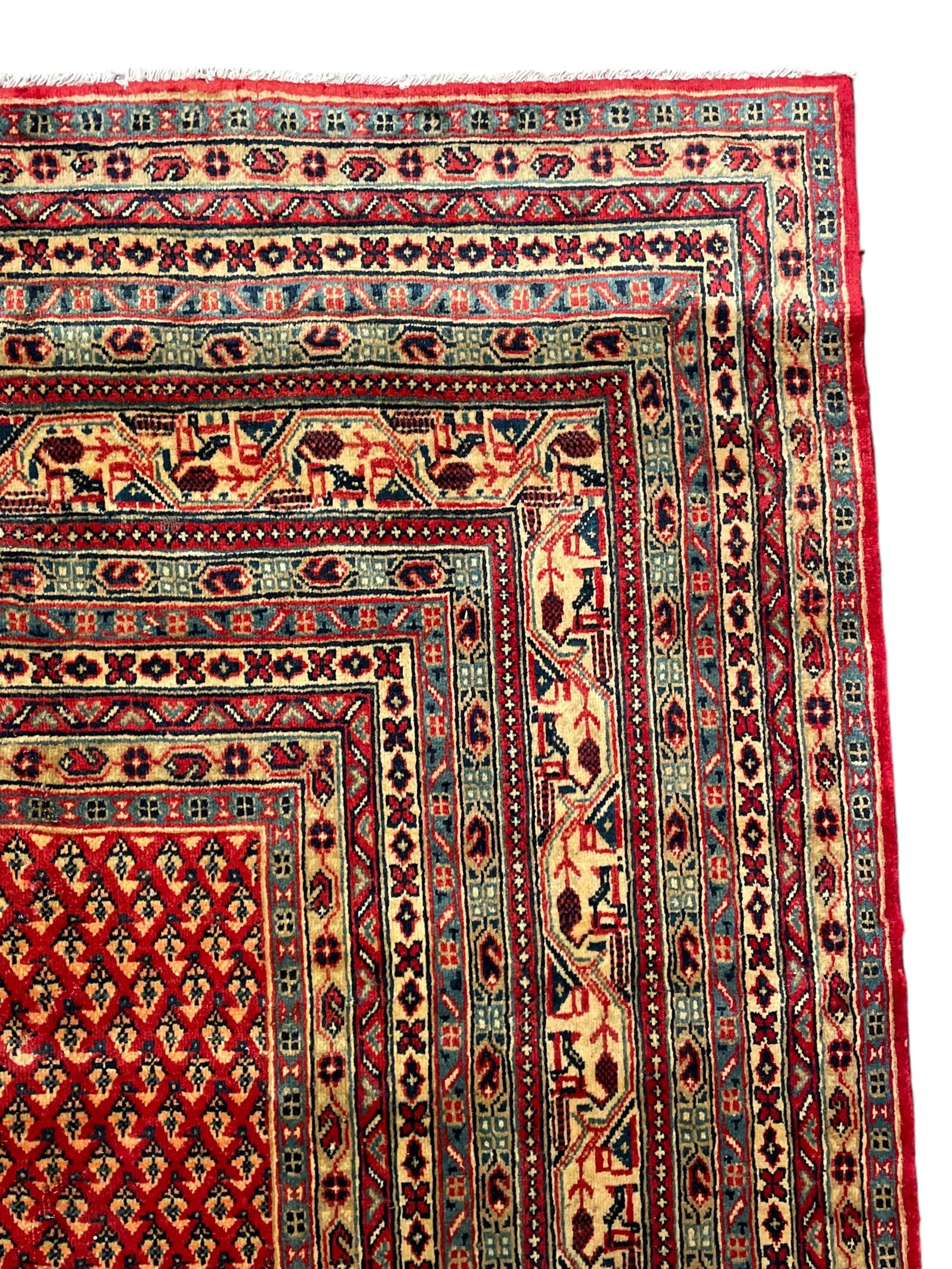 Persian Arak crimson ground carpet, the field decorated profusely with small repeating Boteh motifs, enclosed by multiple border bands decorated with repeating geometric and hook motifs