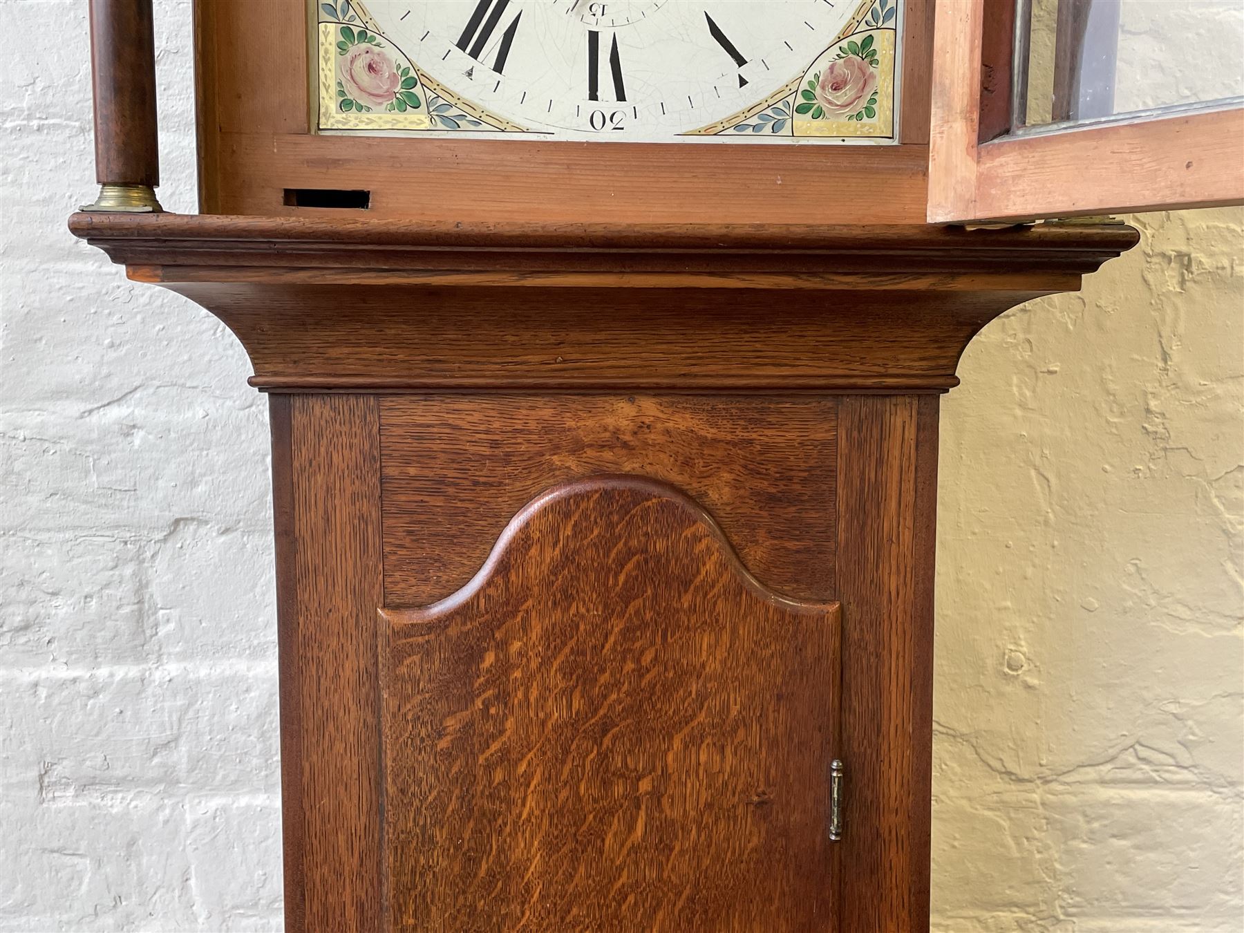 Thirty-hour oak cased longcase clock by  William Bancroft of Scarborough circa 1830, with a swan’s neck pediment, brass patera and three brass spire and ball finials, stepped break arch hood door flanked by plain pillars with brass capitals, trunk with a full length door and curved arch top, on a plain square plinth with bracket feet, painted break arch dial with roman numerals and quarter hour Arabic’s, date recorder (anti clockwise) and matching brass hands, arch painted with a rural scene depicting a ruined tower and cottage with depictions of flowers to the spandrels, dial pinned directly to a chain driven countwheel striking movement, striking the hours on a bell. With weight and pendulum. The Bancroft family were prodigious Scarborough clockmakers during the 18th and 19th century, William Bancroft is recorded as working in Newborough Street from 1820 onwards. 


