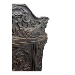 Late 19th century Jacobean revival carved oak armchair, the tall back with arched cresting featuring a stylised foliate mask, flanked by carved scrolls, relief carved panel depicting symmetrical foliage, downscrolled arms, on turned front supports united by stretchers