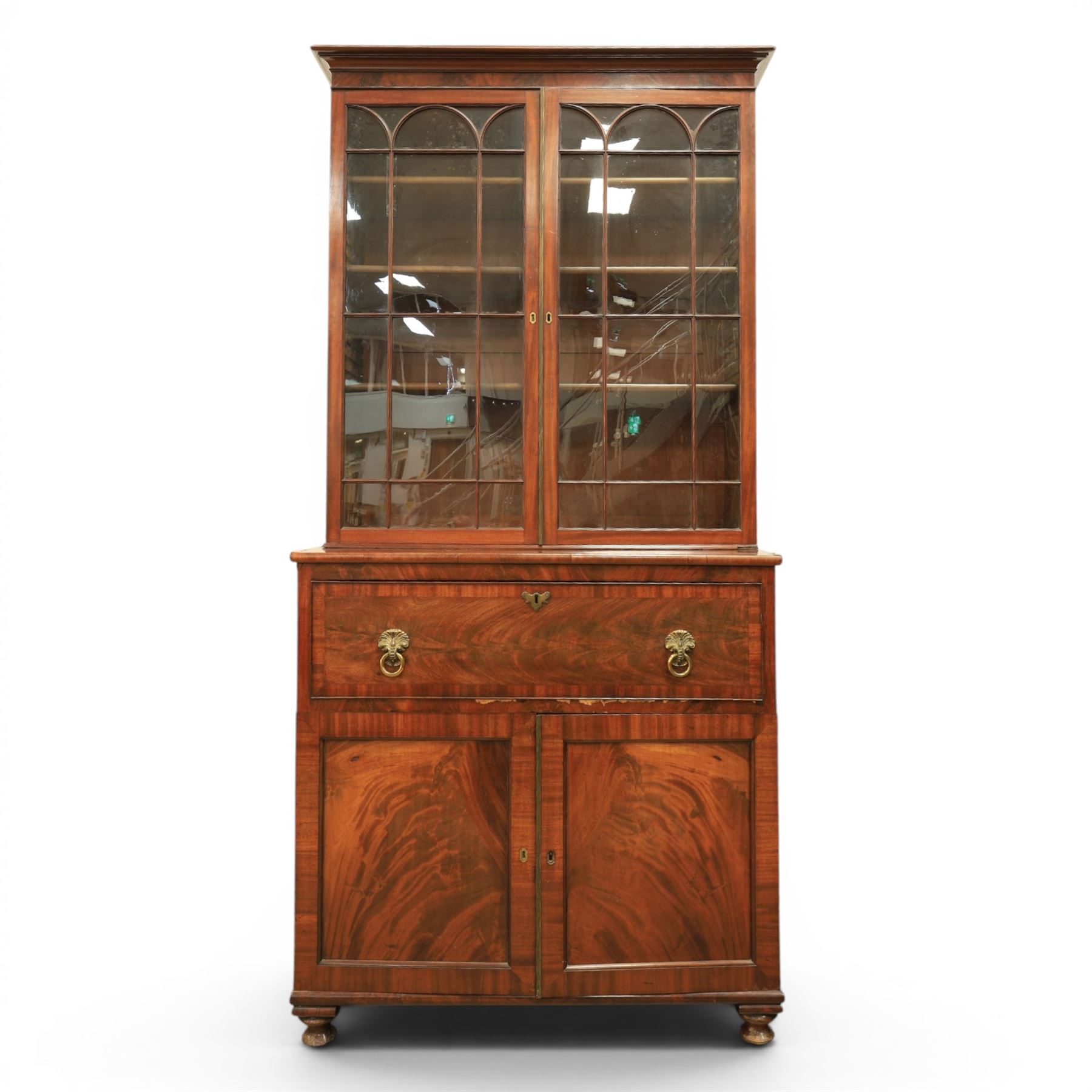 Early 19th century mahogany secretaire-bookcase, projecting cornice above astragal glazed cabinet with adjustable shelved interior, fall front secretaire drawer, fitted interior with pigeonholes and drawers, flame mahogany fronted cabinet with three drawers, on turned supports 