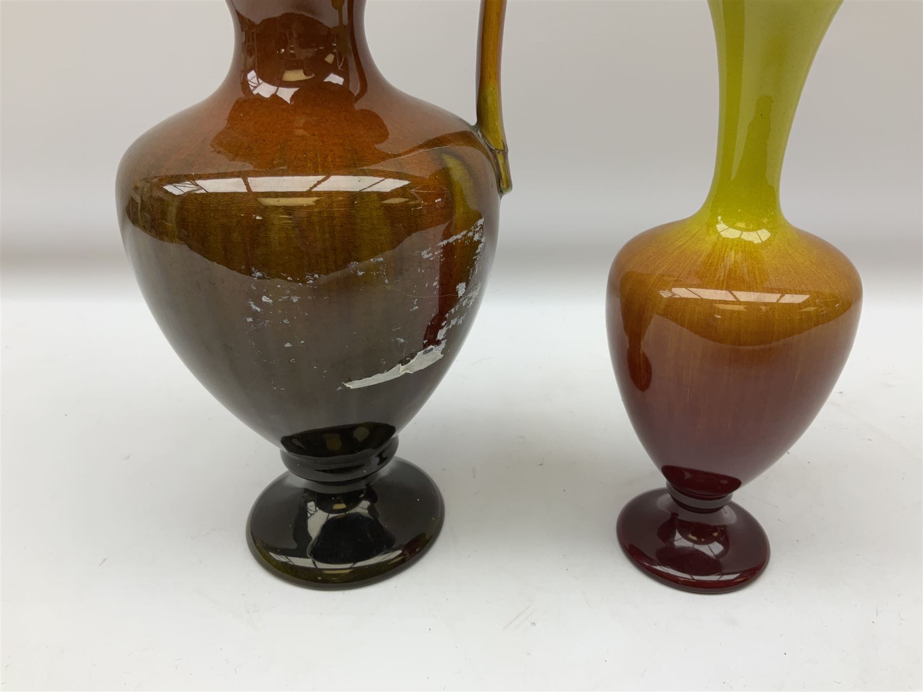 Linthorpe pottery vase with crimped rim and ovoid body, Linthorpe jug with high loop handle and crimped spout, a pair of candlesticks with a green, brown glaze and other similar pottery 
