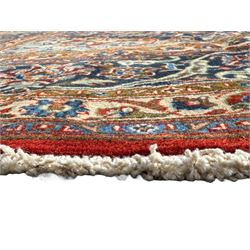 Central Persian Kashan carpet, the red field centred by a large multi-lobed floral medallion, flanked by corner spandrels in navy, enclosed by multiple scrolling floral borders, fringed to two ends
