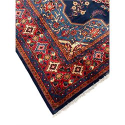 Persian Veis indigo ground carpet, the field with large pole medallion decorated with Herati motifs and surrounded by floral sprays, crimson ground border with repeating cross motifs and stylised flower heads, within guard stripes 