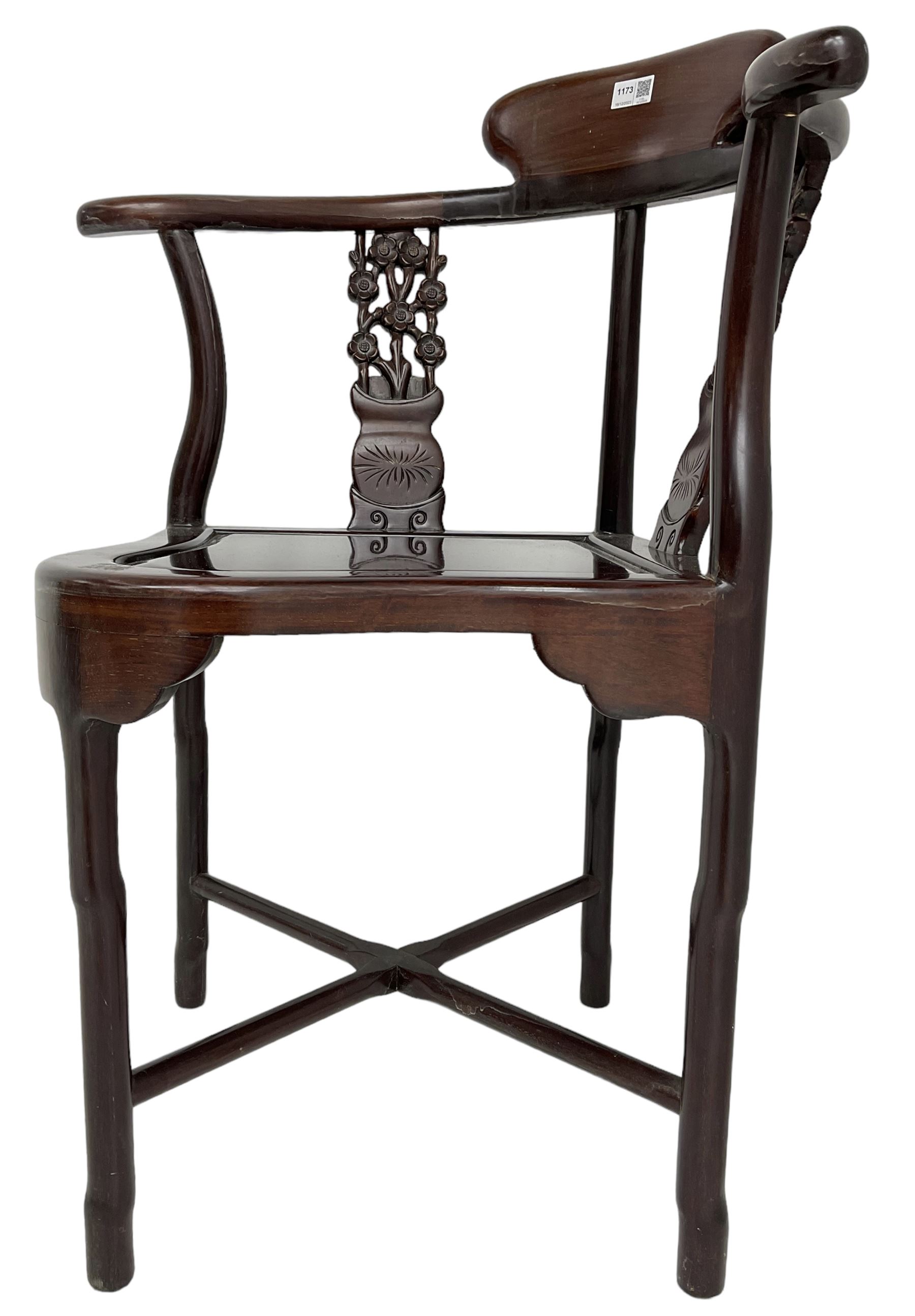 Chinese carved hardwood corner chair, outswept arms over pierced and carved floral splats, raised on shaped cylindrical supports united by X-stretcher