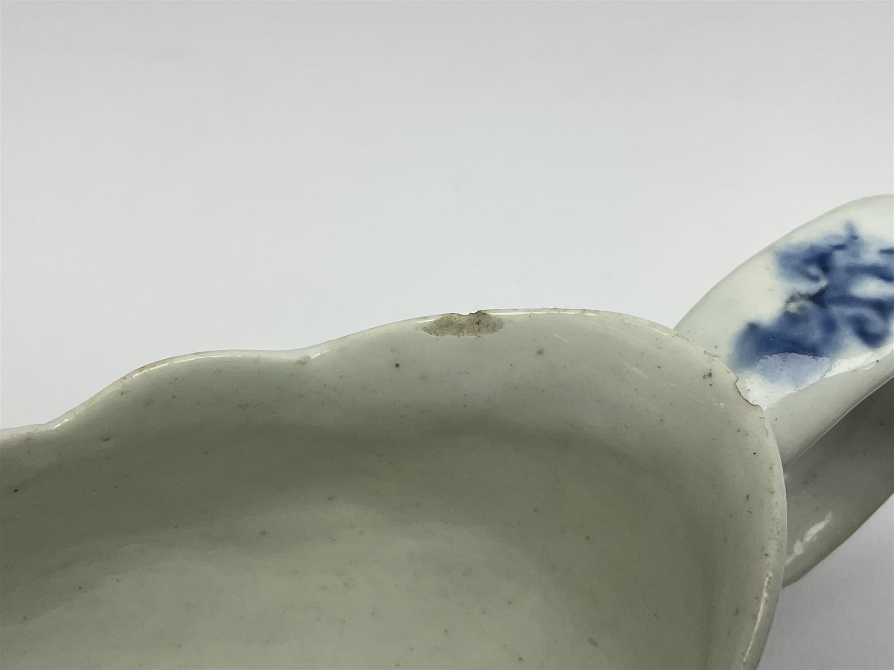 Large 18th century Lowestoft sauce boat, circa 1770, the body decorated with Hughes type floral moulding, and painted in underglaze blue with an Oriental landscape, and foliate sprigs, L23cm
