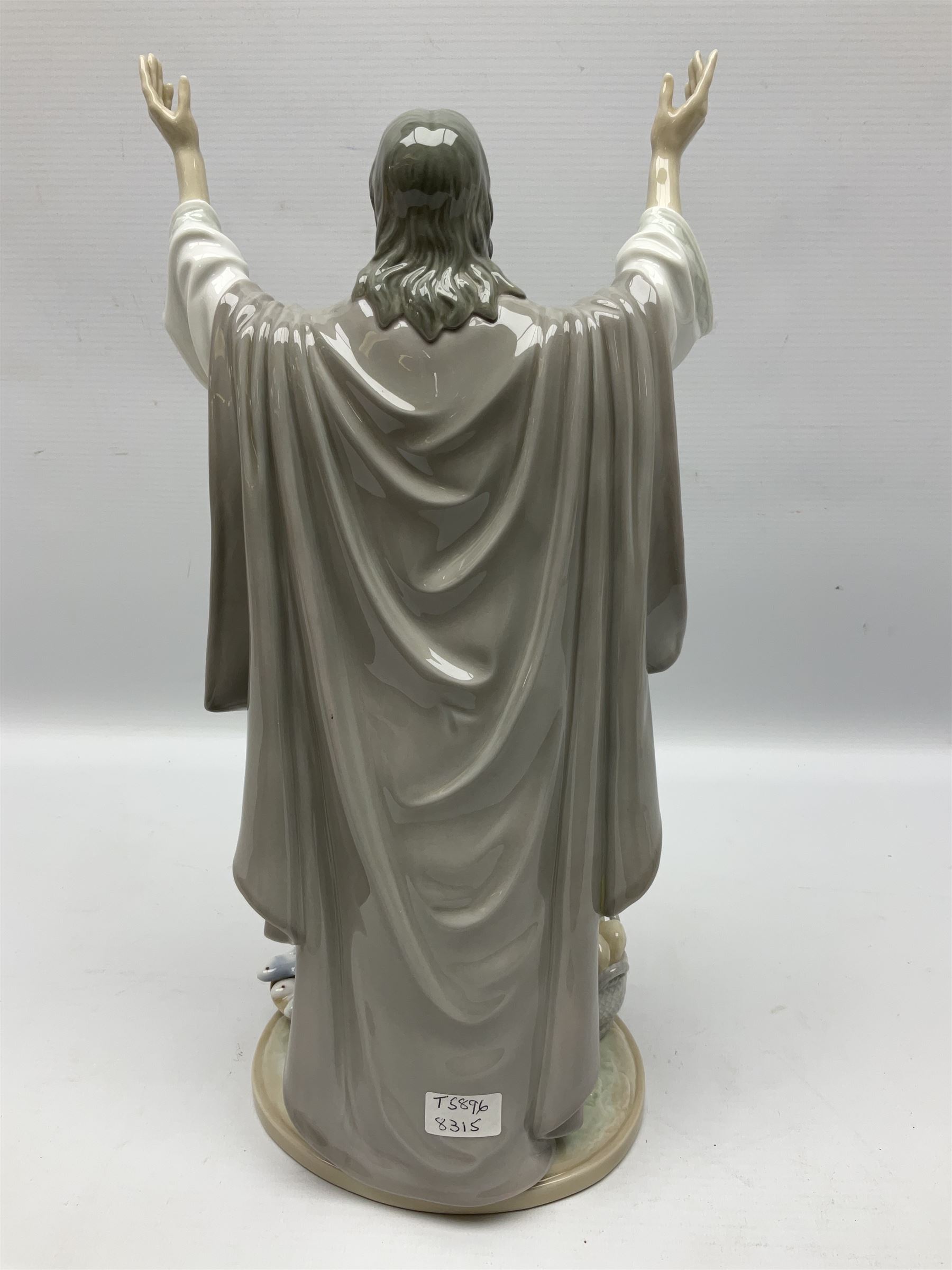 Lladro figure, The Loaves and Fishes, modelled as Jesus Christ with arms raised standing beside a basket of loaves and a basket of fish, sculpted by Salvador Furió, with original box, no 5896, year issued 1992, year retired 1997, H35cm