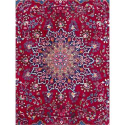 Pair of Persian wool rugs, each with rich red ground, one centred with a diamond-shaped medallion and navy spandrels within a floral field, the other with radiating floral medallion and scrolling foliate motifs, both enclosed by multiple borders with palmette and flowerhead designs, from the region of Kashan 291x376, 299 x 378 