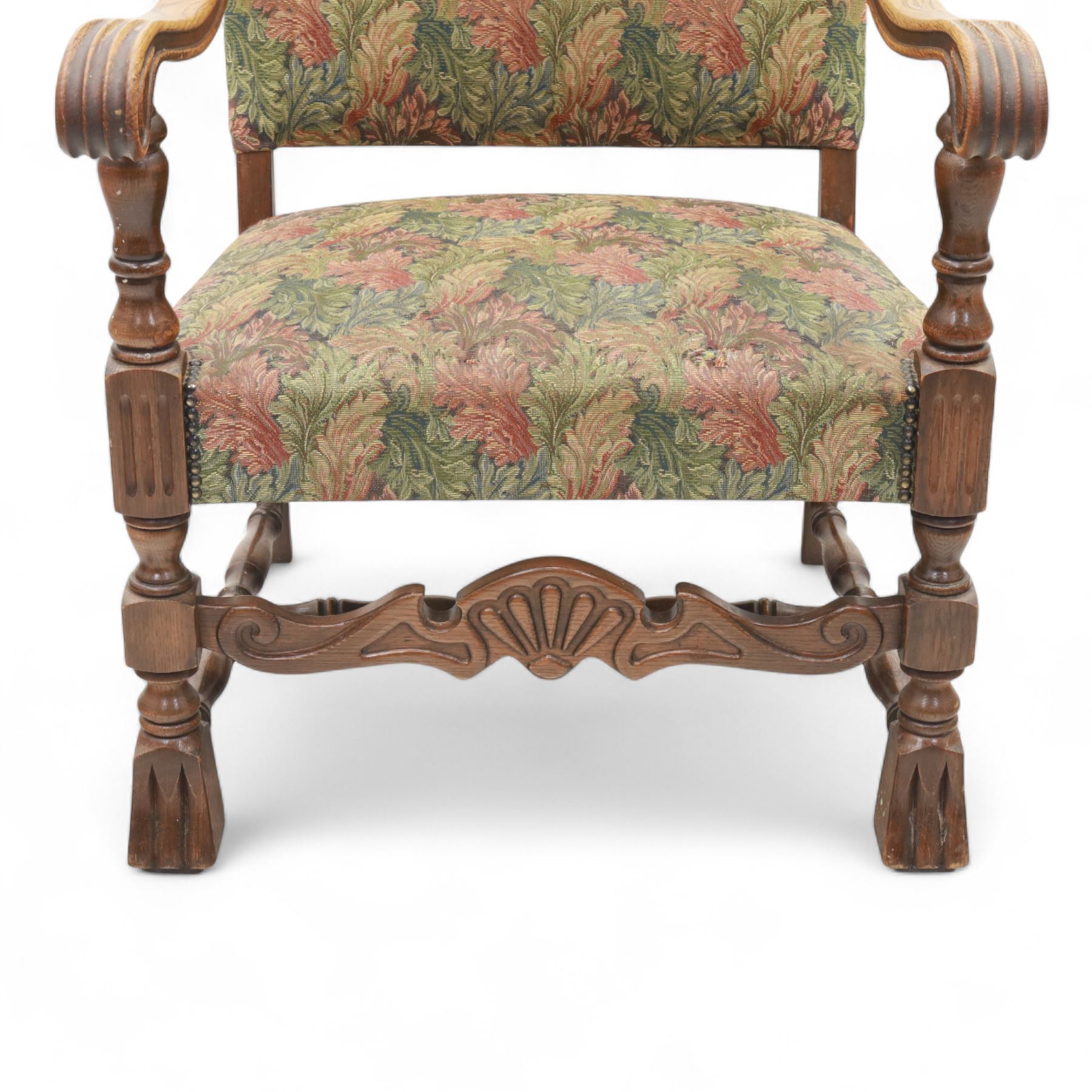 Early 20th-century Jacobean revival open oak armchair, arched padded back, and seat button upholstered  in foliate tapestry style fabric, with scroll carved arms on turned supports, raised on block supports united by turned shaped stretchers 