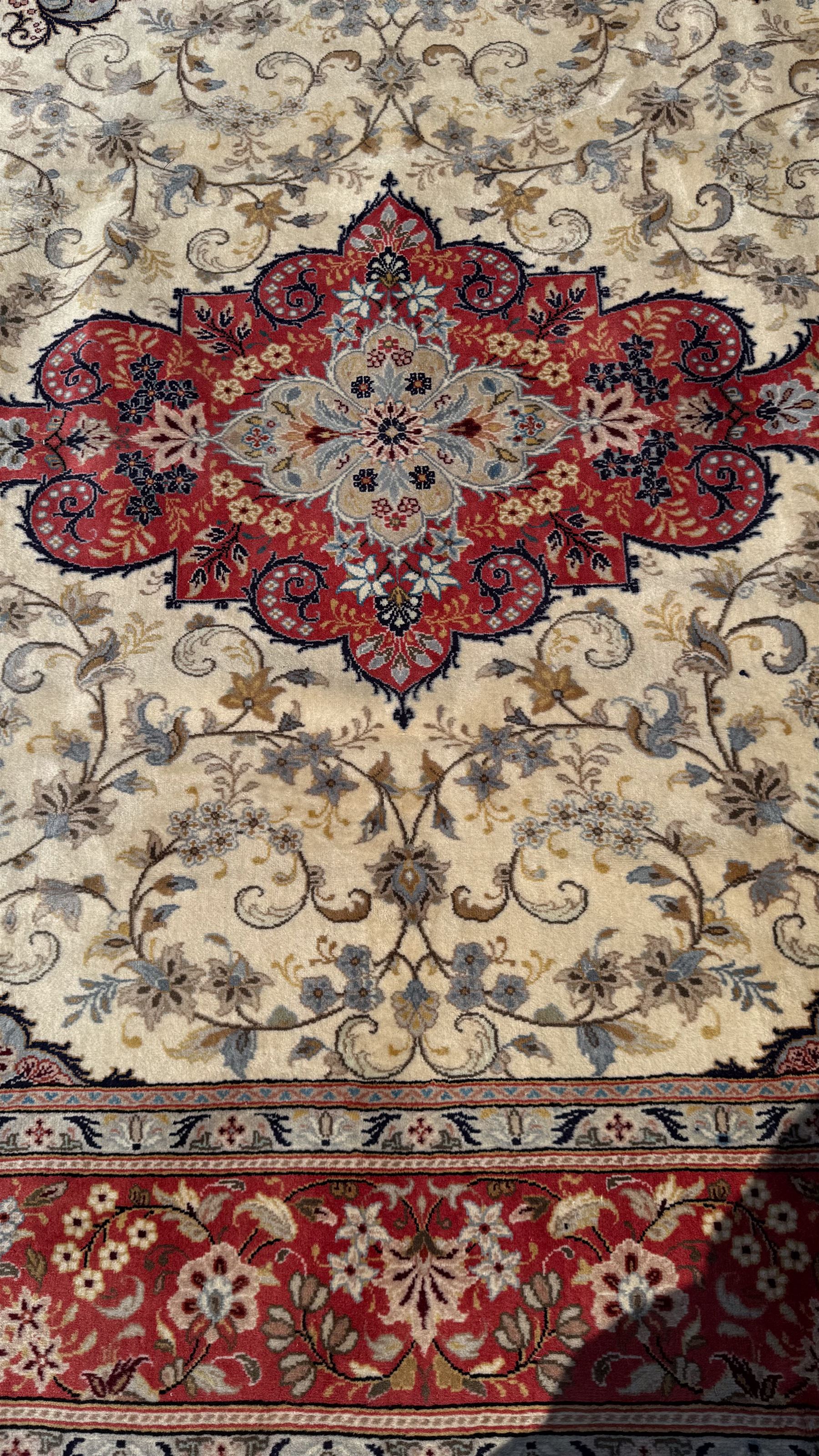 Central Persian Kashan rug, ivory and teal ground, overall geometric design, angular interlaced decorated field with stylised plant motifs, crimson ground, central medallion, the crimson main border band decorated with geometric motifs