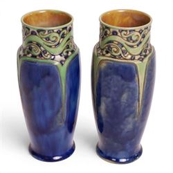 Royal Doulton - Pair of Art Nouveau vases, designed by Francis Pope, with scroll work to the collar, in tones of green and blue, with impressed mark and no. 8138 beneath, H26cm