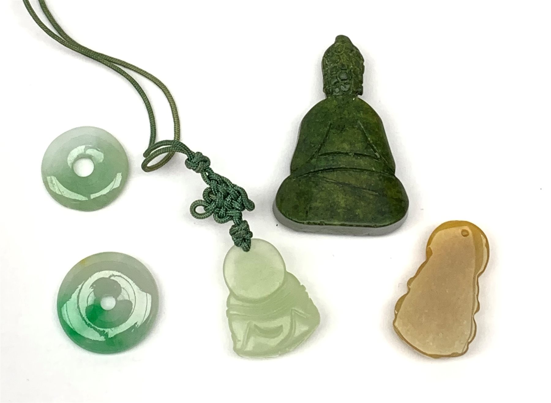 A jade pendant modelled as a hotai, H3.5cm, two small jade pi discs, a further carved pendant modelled as a buddah, and a carved soapsone figure of similar form. 