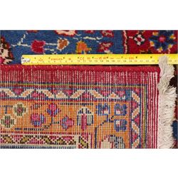 Persian Kashan hand-knotted rug, madder red ground centred by circular floral medallion with pendants, surrounded by scrolling vines, palmettes and flowerheads, dark navy spandrels, enclosed by dark navy floral border with multiple guard stripes