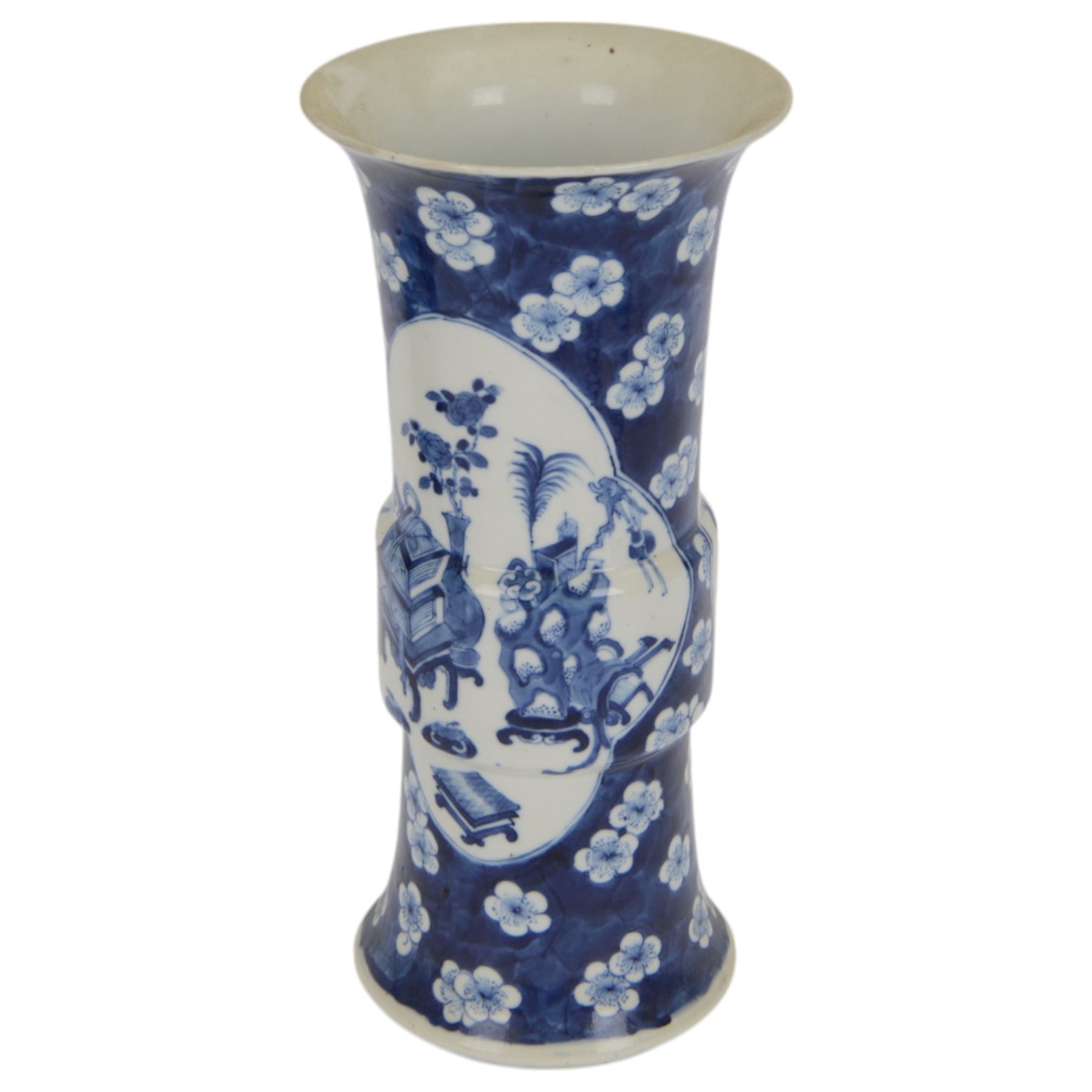 Late 19th century Chinese blue and white gu beaker vase, decorated with two lobed reserves containing precious objects, against a prunus and cracked ice ground, with apocryphal Kangxi mark beneath, H30.5cm