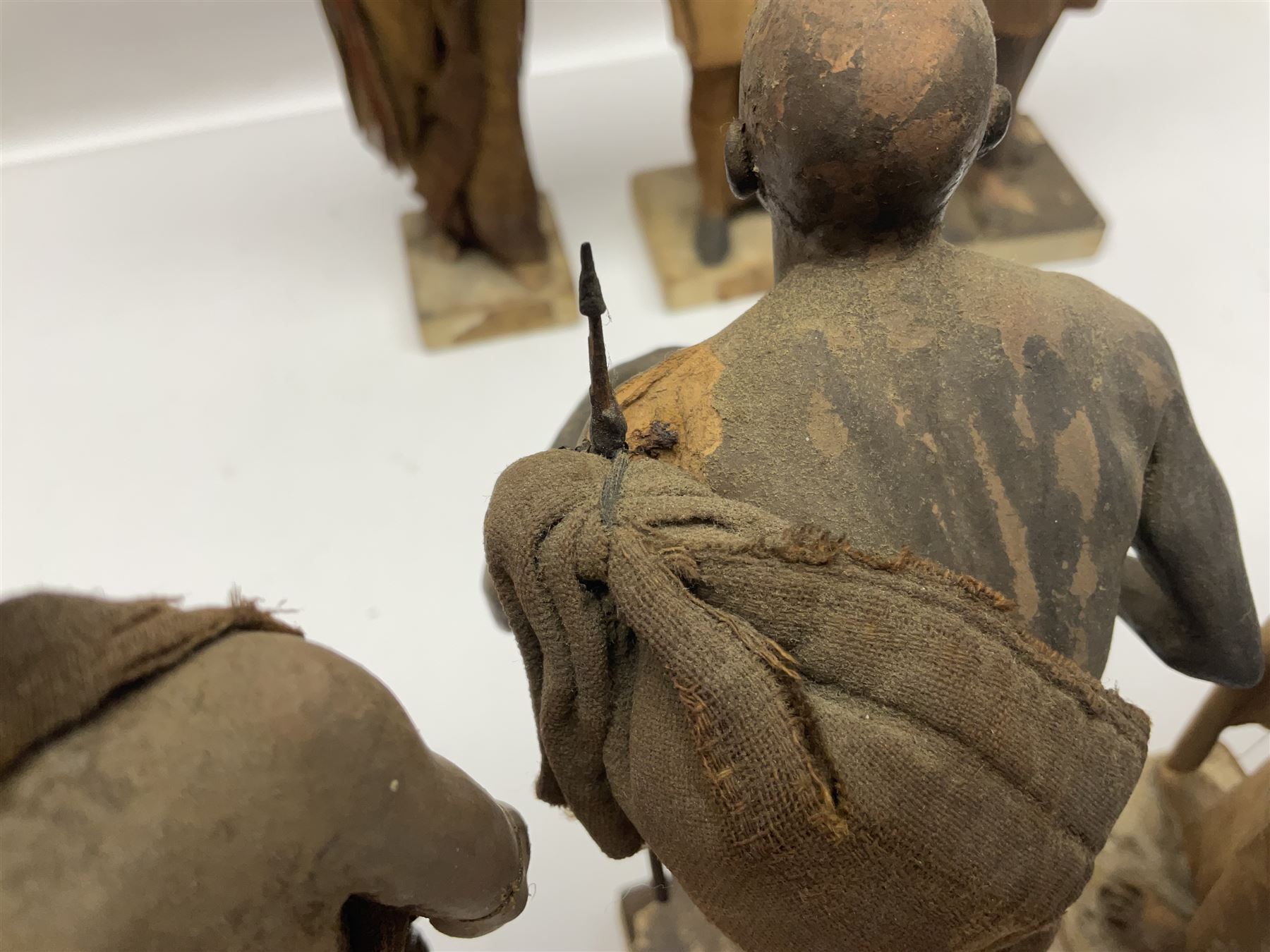Seven 19th Century Indian clay dolls, possibly Krishnanagar, each figure with painted details, wearing cloth garments, standing on rectangular bases, some with paper label to the base, H25cm