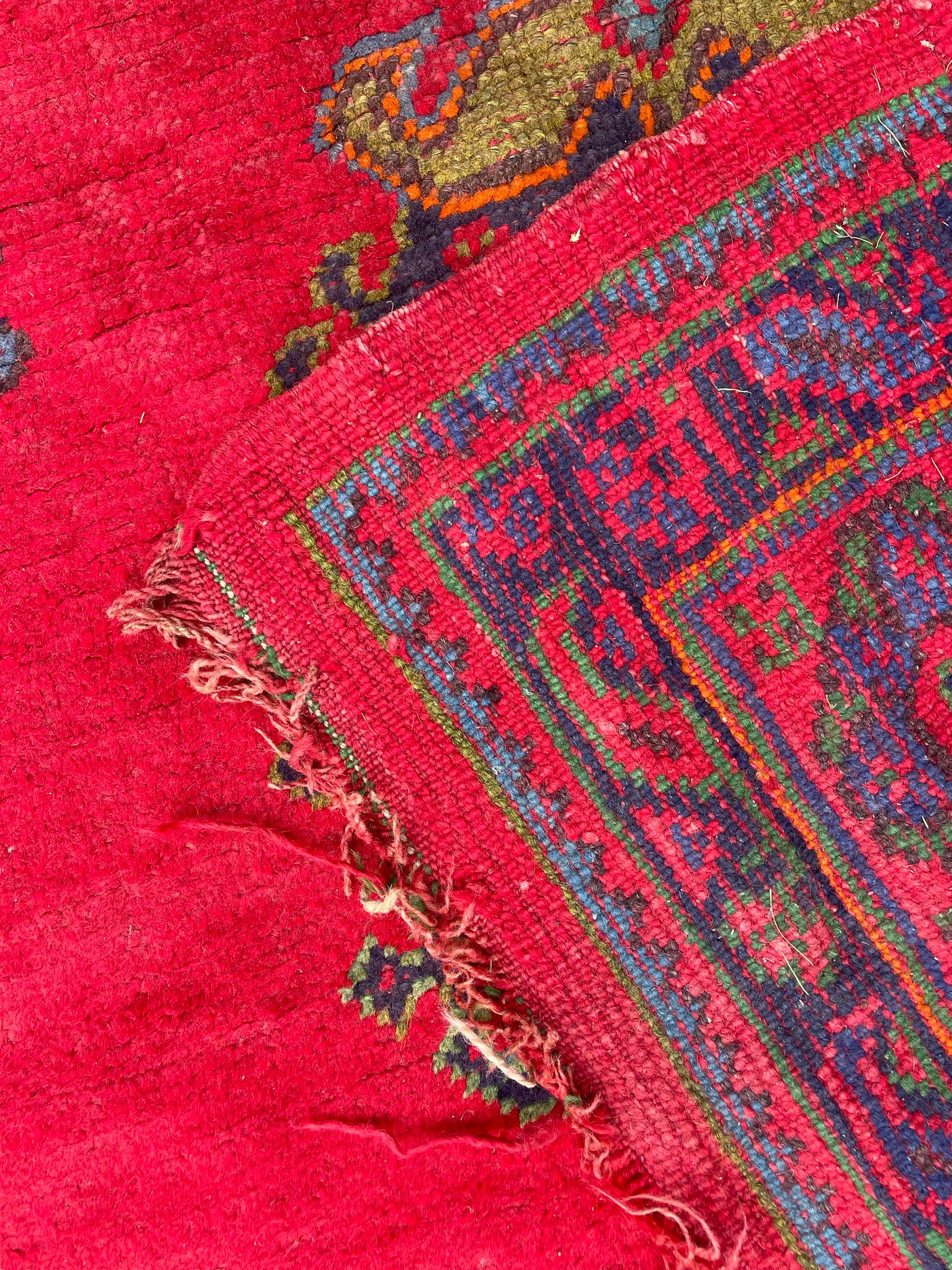 Early 20th century Western Anatolia Turkish Oushak crimson ground carpet, the field decorated with rows of Herati and Palmette medallions, the main border decorated with stylised flower head motifs within guard stripes