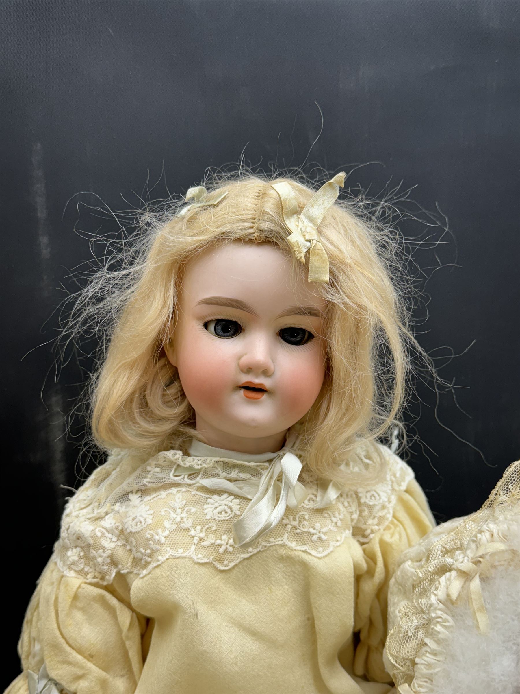 Two German bisque head dolls, to include a Franz Schmidt example with blue glass eyes and an Armand Marseille 590 example with applied hair, together with a Schoenau & Hoffmeister bisque doll's head, pair of doll's hands and a collection of clothing