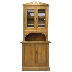 Late 19th century stripped pine dresser, shaped sloping pediment over two glazed doors, rectangular top over double panelled cupboard, on plinth base
