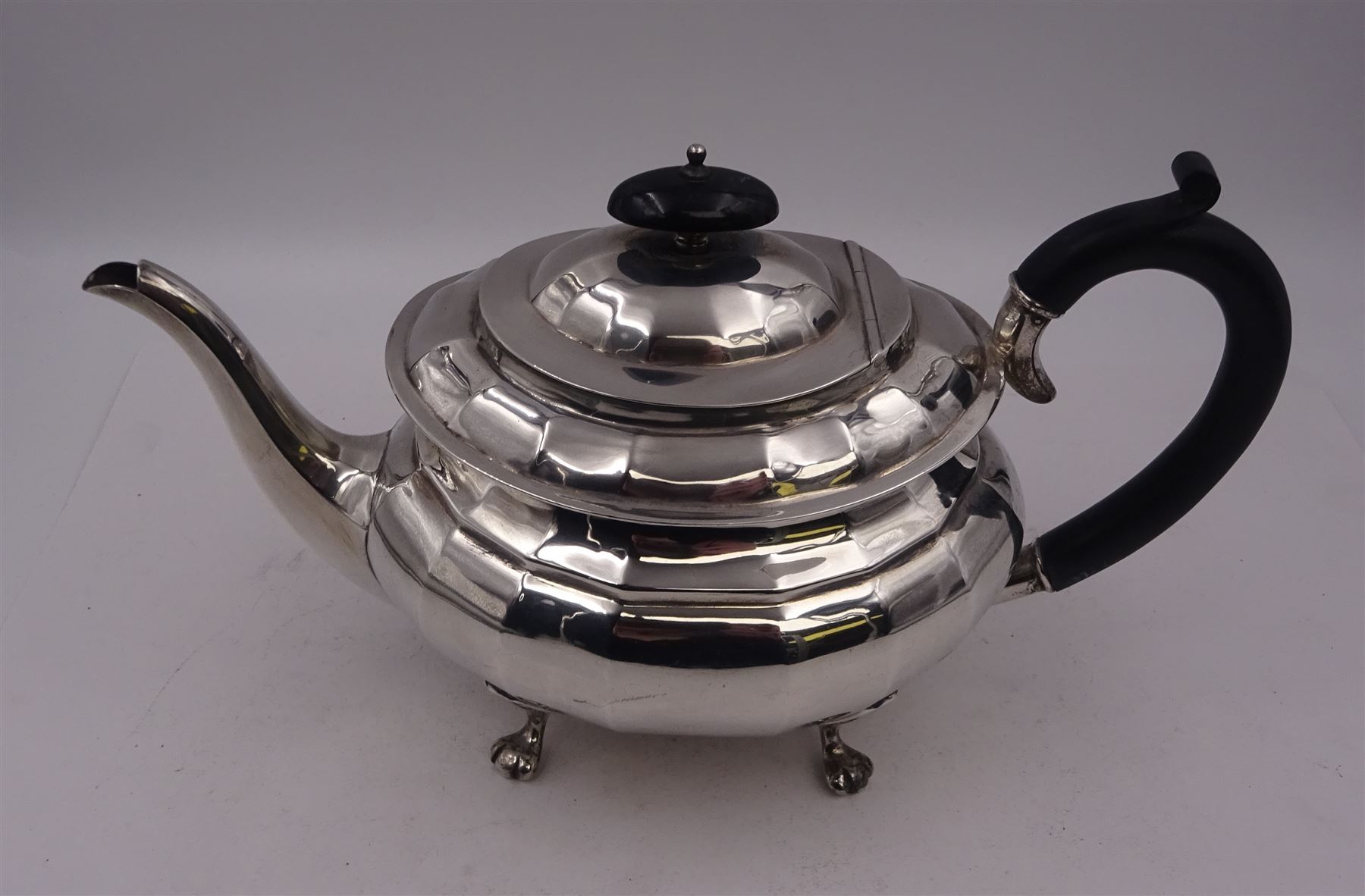 1920s silver teapot, of oval faceted form, with Bakelite type handle and finial, with presentation engraving to body, and upon four paw feet, hallmarked Northern Goldsmiths Co, Birmingham 1929, H16cm
