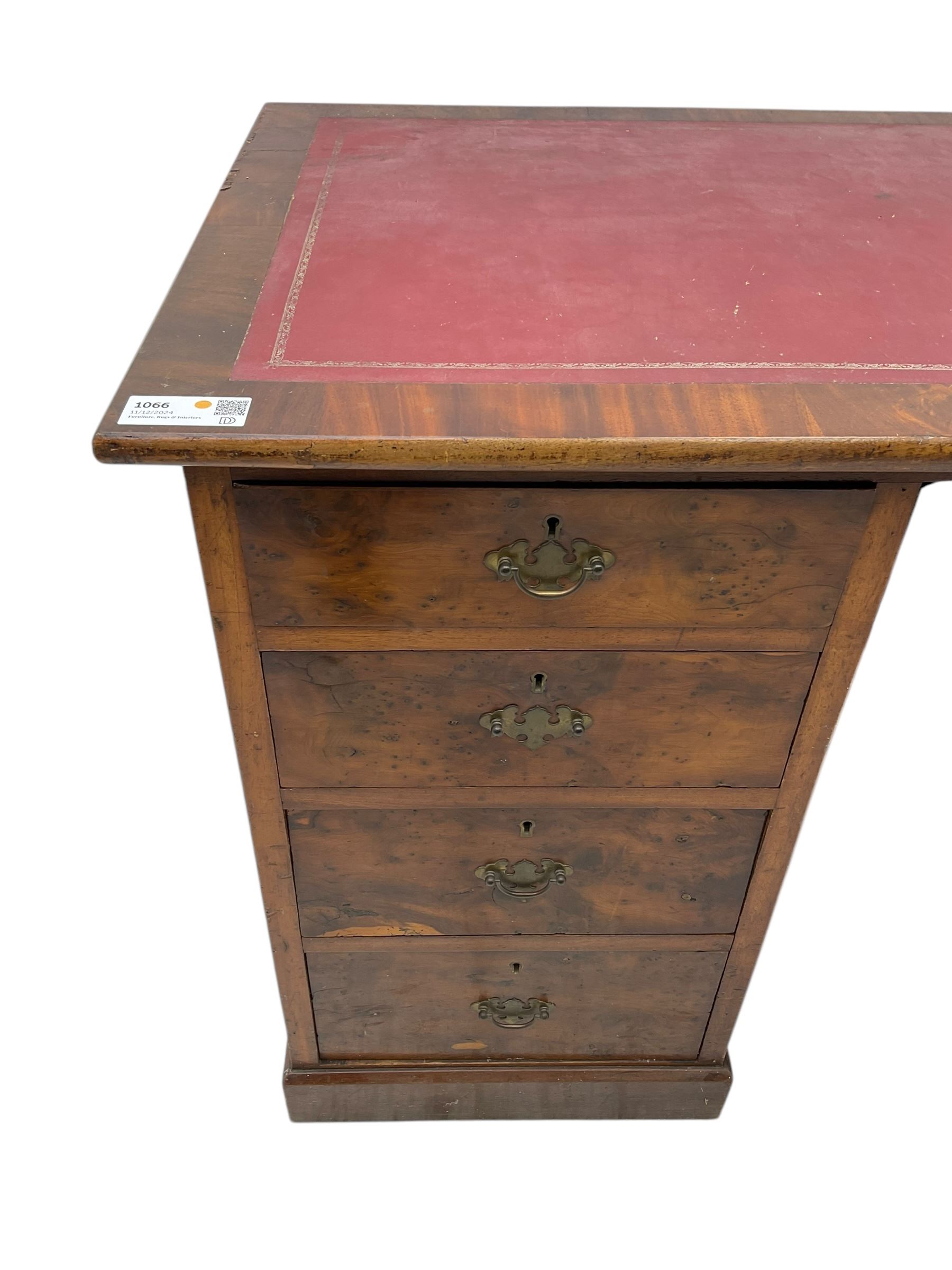 Late 19th to early 20th century walnut pedestal desk, rectangular top inset with red tooled leather writing surface, over a central frieze drawer flanked by two pedestals, each fitted with four graduated drawers with brass escutcheons and drop handles, the whole raised on a plinth base