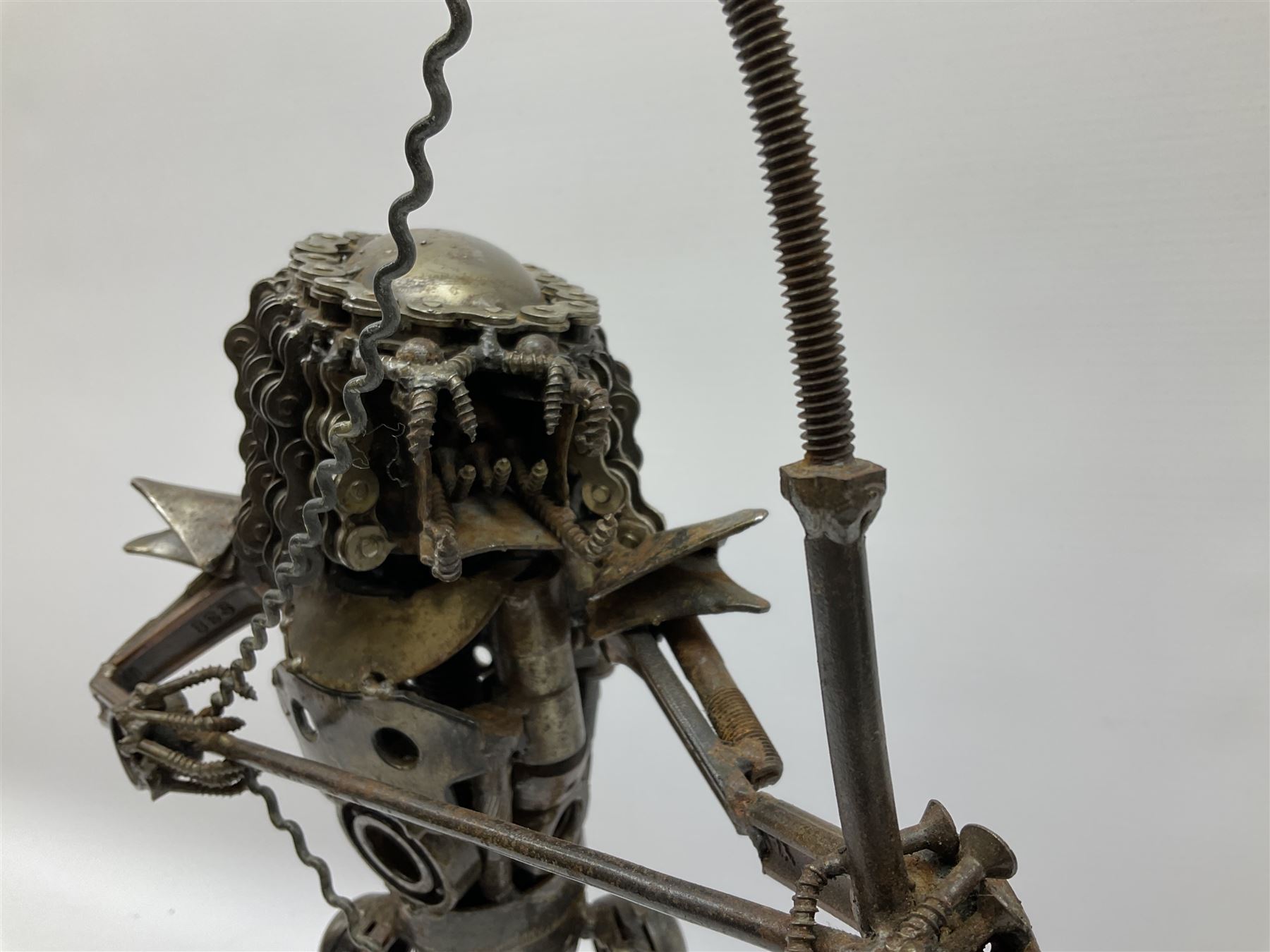 Predator metal sculpture, made with scrap metal, with articulated body, bike chain hair, and bow and arrow, H45cm