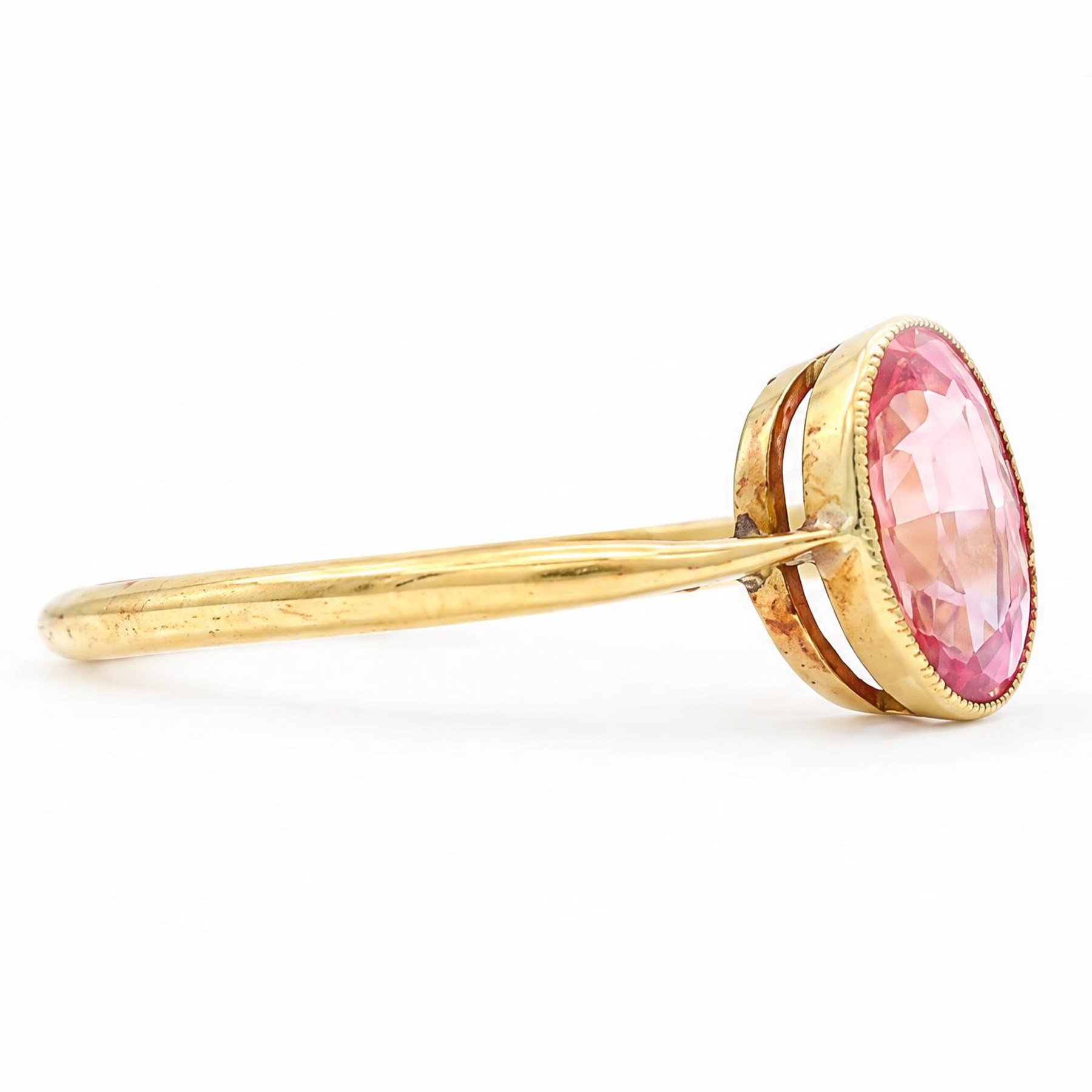 Early 20th century gold padparadscha sapphire ring, milgrain set with a single oval cut sapphire of approx 1.05 carat