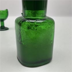 Pair of 19th century green glass eye baths, together with three green glass bottles 