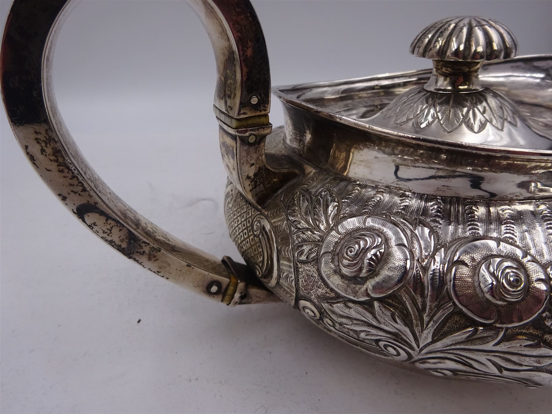 George III Irish silver teapot, of squat circular form, the body with repousse and chased floral and C scroll decoration, with capped C handle and ivory insulators, engraved to base 'Presented to Troop Sergeant Major John Percival, of the 4th Dragoon Guards by Alex D. Tait, Esq, late Captain in that corps as a mark of approbation of his steady and upright conduct when Sergeant Major of his Troop, Dublin, June 2nd 1843', hallmarked William Law, Dublin 1817, H12.5cm, This item has been registered for sale under Section 10 of the APHA Ivory Act