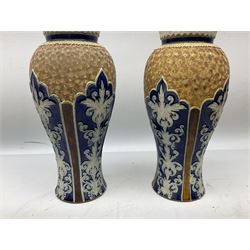 Pair of Royal Doulton Lambeth stoneware baluster vases, decorated in light relief with panels of foliage on blue ground, with gilt scrolls above, impressed mark beneath, 28cm high
